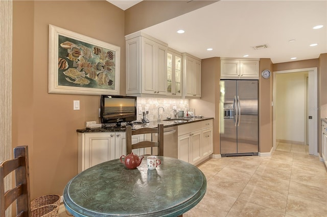 kitchen with stainless steel appliances, tasteful backsplash, dark stone counters, and sink