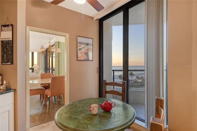 dining room with ceiling fan with notable chandelier, light tile patterned floors, expansive windows, and a water view