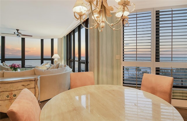 dining area featuring ceiling fan with notable chandelier, crown molding, and a water view