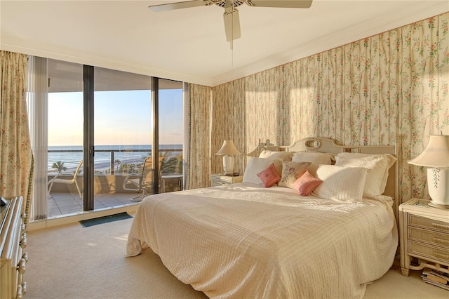 carpeted bedroom with a water view, a wall of windows, access to outside, and ceiling fan