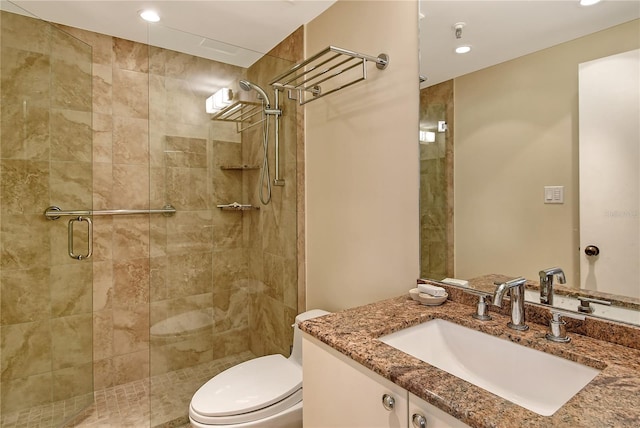 bathroom with toilet, vanity, and a shower with door