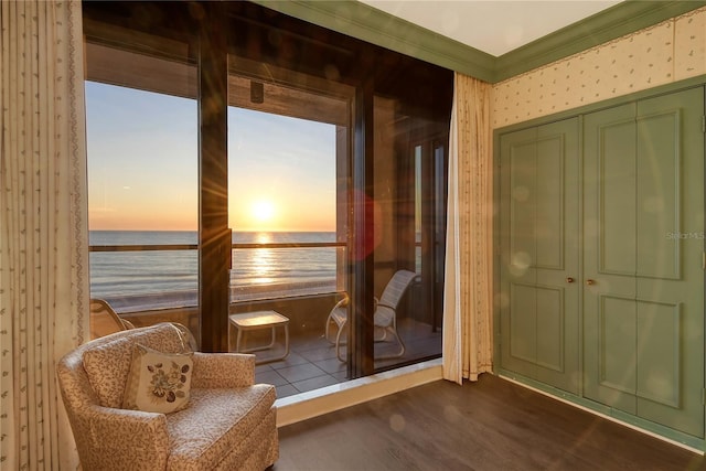 sitting room with dark hardwood / wood-style flooring, crown molding, and a water view