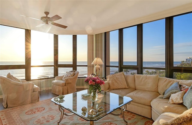 living room with ceiling fan, a wealth of natural light, and a water view