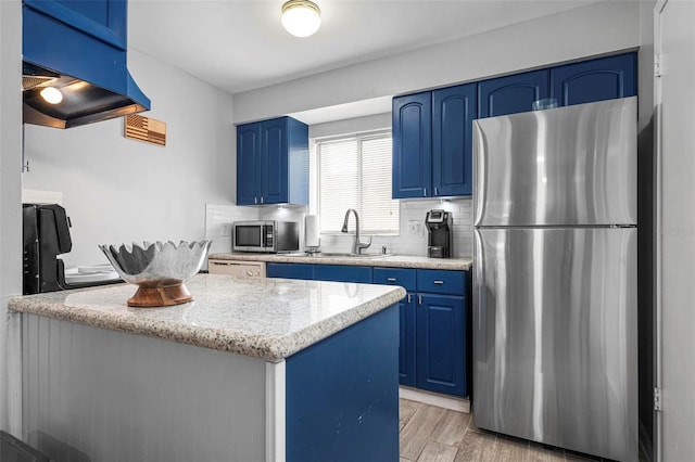 kitchen with stainless steel appliances, blue cabinets, a center island, and sink