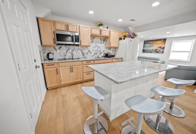 kitchen with white refrigerator, light stone countertops, decorative backsplash, and black electric cooktop
