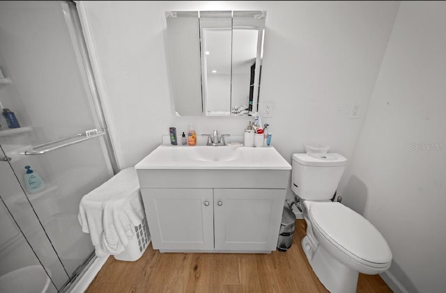 bathroom with vanity, hardwood / wood-style flooring, a shower with door, and toilet