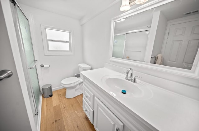 bathroom featuring wood-type flooring, toilet, walk in shower, and vanity