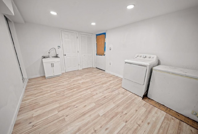laundry area with sink, light hardwood / wood-style floors, and separate washer and dryer