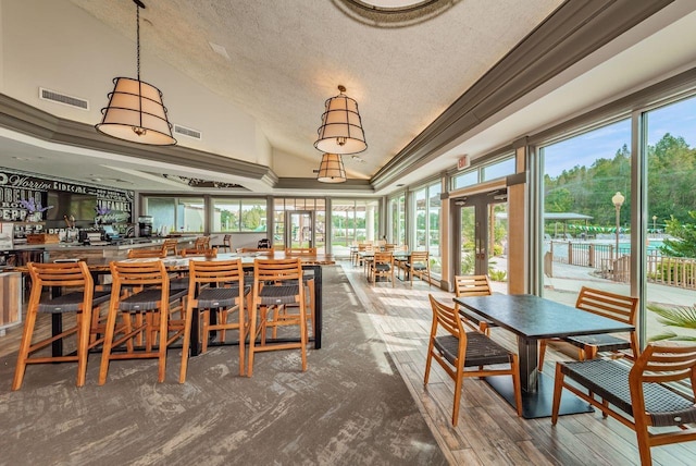 dining room with a textured ceiling, crown molding, lofted ceiling, and carpet floors