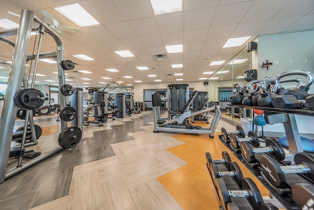 exercise room featuring ceiling fan and a paneled ceiling