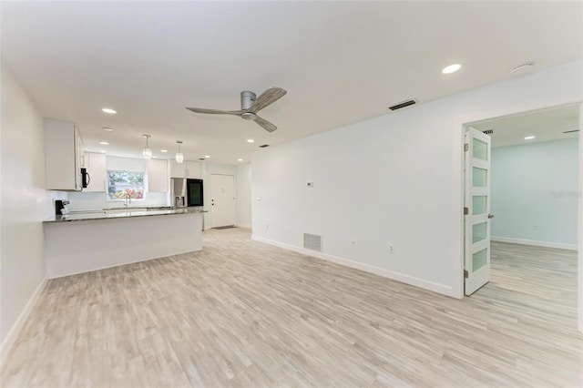 unfurnished living room with light wood-type flooring, ceiling fan, and sink