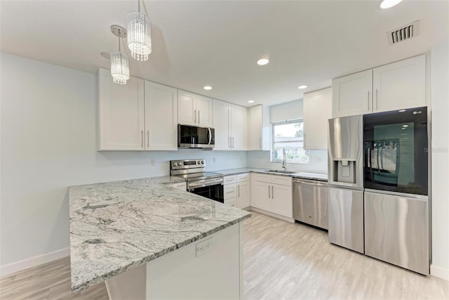 kitchen with light stone counters, hanging light fixtures, stainless steel appliances, white cabinets, and sink