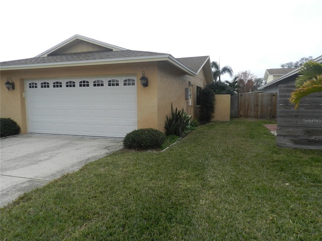 view of home's exterior featuring driveway, a garage, fence, a yard, and stucco siding