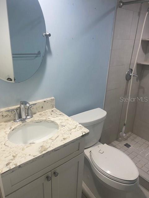 bathroom with toilet, a stall shower, and vanity