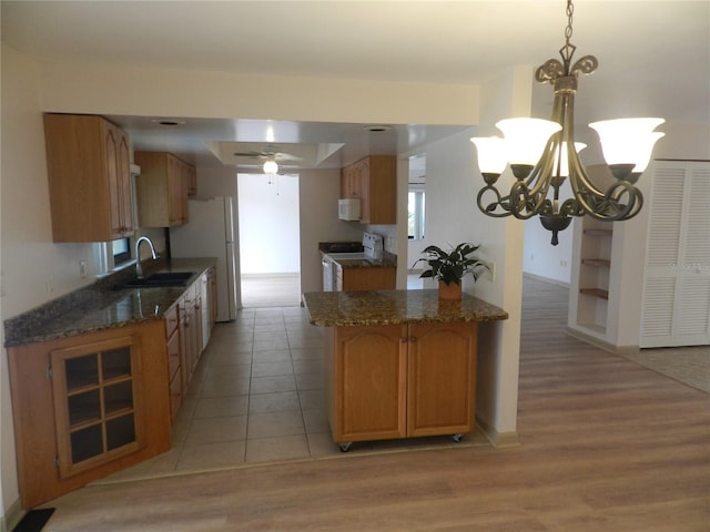 kitchen with light wood-style floors, white appliances, brown cabinets, and a sink