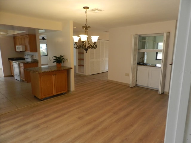 kitchen featuring light wood-style flooring, white appliances, visible vents, baseboards, and pendant lighting