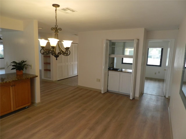 kitchen featuring light wood finished floors, baseboards, visible vents, hanging light fixtures, and an inviting chandelier