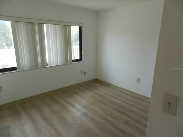 spare room with baseboards and wood finished floors