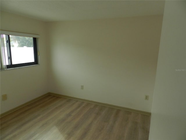 empty room featuring light wood-type flooring and baseboards