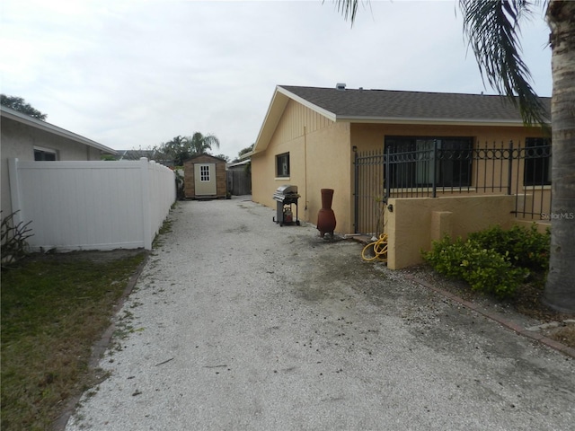 view of home's exterior with a storage shed, fence, an outdoor structure, and stucco siding