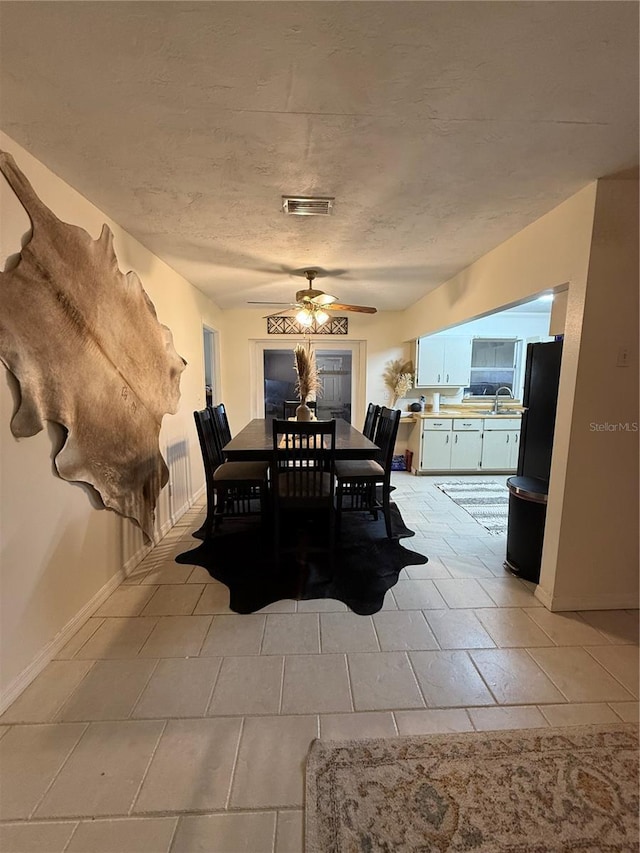 dining space with sink, a textured ceiling, and ceiling fan