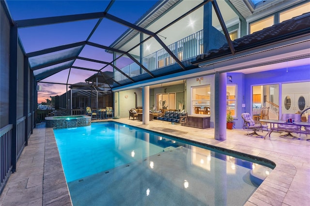 pool at dusk featuring a lanai, an outdoor living space, a patio area, and an in ground hot tub