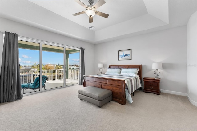 carpeted bedroom with ceiling fan, access to exterior, and a tray ceiling