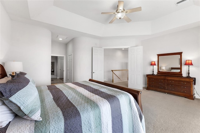 carpeted bedroom with a raised ceiling, ceiling fan, and a closet