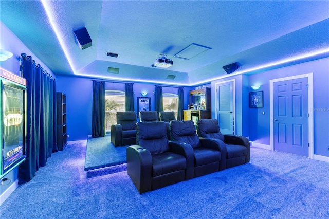 carpeted home theater room with a textured ceiling and a raised ceiling