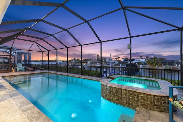 pool at dusk with a water view, a patio, glass enclosure, and an in ground hot tub