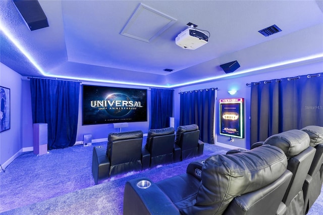 home theater room with a tray ceiling and carpet flooring