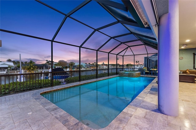 pool at dusk with a lanai, a water view, an in ground hot tub, and a patio