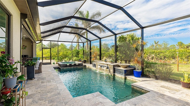 view of pool with a patio, glass enclosure, pool water feature, and an in ground hot tub