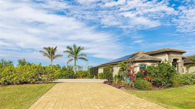 view of front facade featuring a front lawn and solar panels