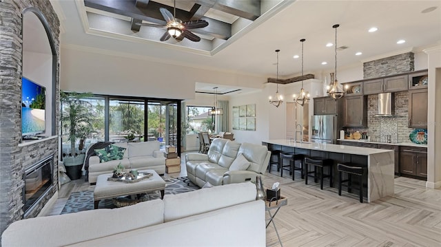 living room featuring light parquet flooring, ornamental molding, a fireplace, ceiling fan, and coffered ceiling