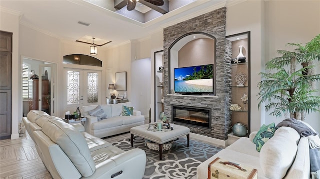 living room featuring french doors, crown molding, parquet floors, and a stone fireplace