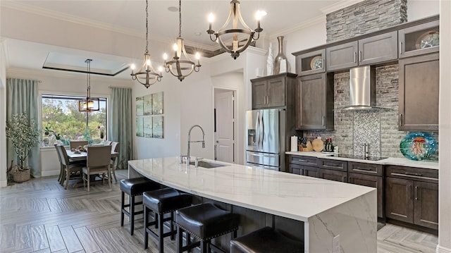 kitchen with stainless steel fridge with ice dispenser, light parquet flooring, wall chimney exhaust hood, and an island with sink