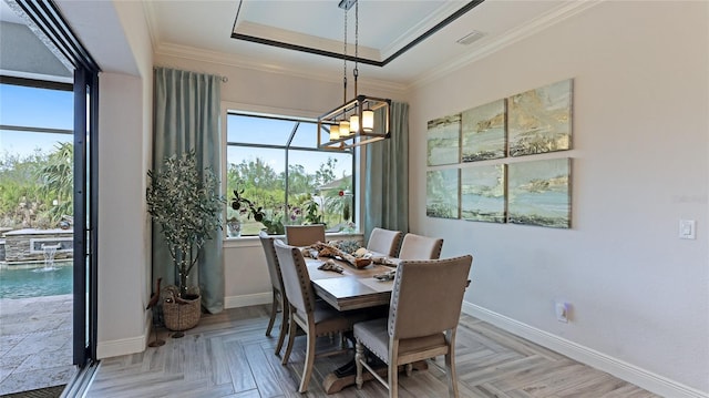 dining area featuring ornamental molding, an inviting chandelier, a raised ceiling, and light parquet flooring