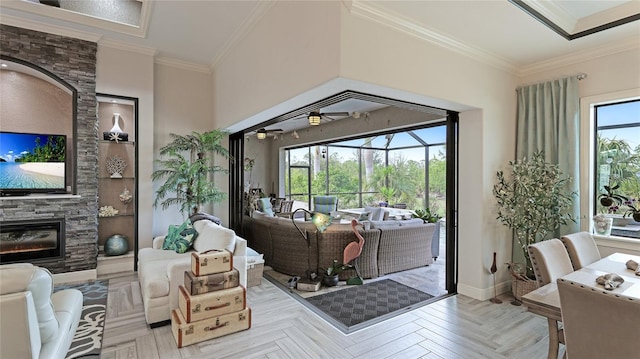 living room with light parquet floors, ceiling fan, built in features, crown molding, and a stone fireplace