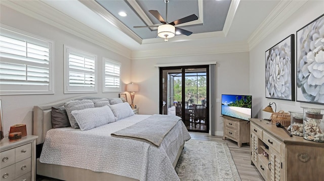 bedroom with light hardwood / wood-style floors, crown molding, ceiling fan, a tray ceiling, and access to exterior