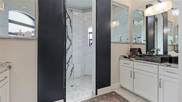 bathroom with tiled shower, tile patterned flooring, and vanity