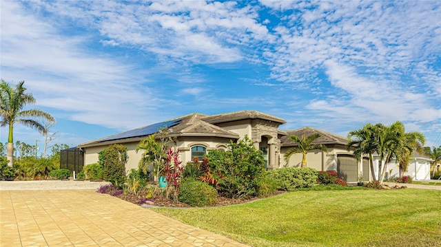 mediterranean / spanish home featuring solar panels, glass enclosure, a front lawn, and a garage