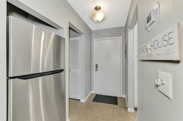 entryway featuring light tile patterned floors and a textured ceiling