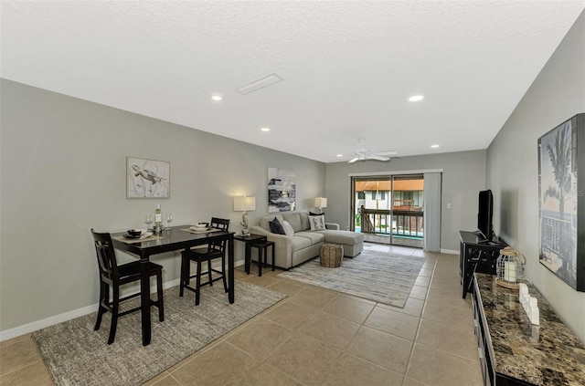 living room with ceiling fan, light tile patterned flooring, and a textured ceiling