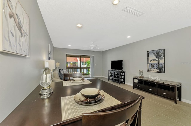 tiled dining area with a textured ceiling and ceiling fan