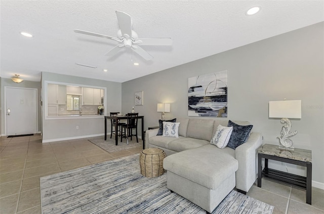 living room with ceiling fan, a textured ceiling, and tile patterned flooring