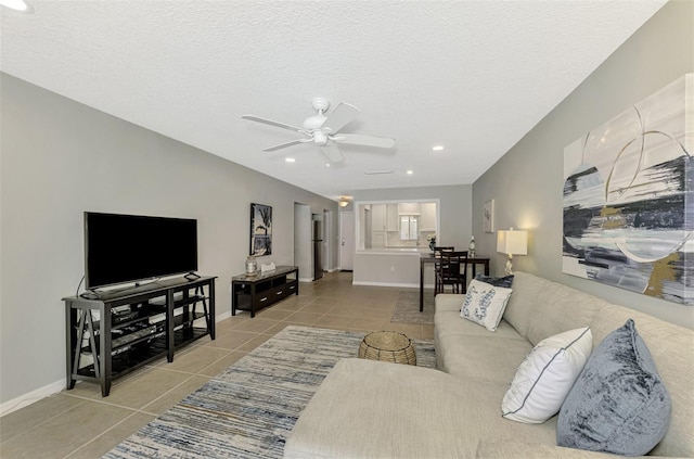 living room featuring ceiling fan, light tile patterned flooring, and a textured ceiling