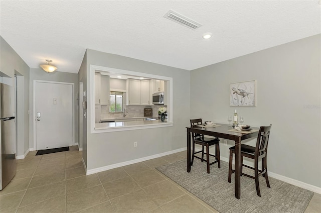 dining space with sink, light tile patterned flooring, and a textured ceiling