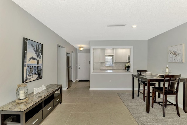 tiled dining room featuring a textured ceiling