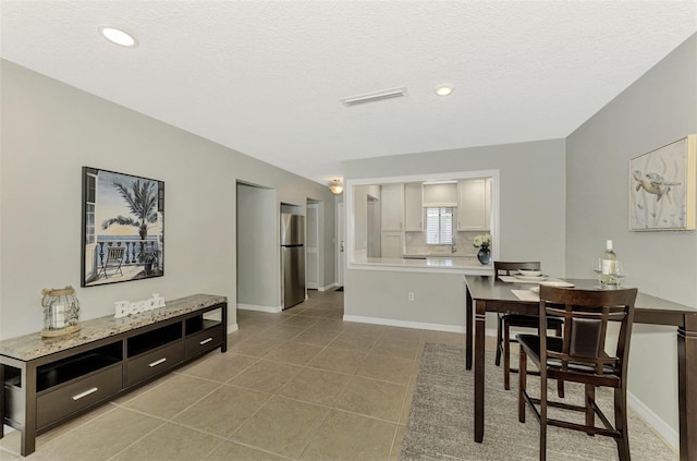 dining space featuring a textured ceiling and light tile patterned floors